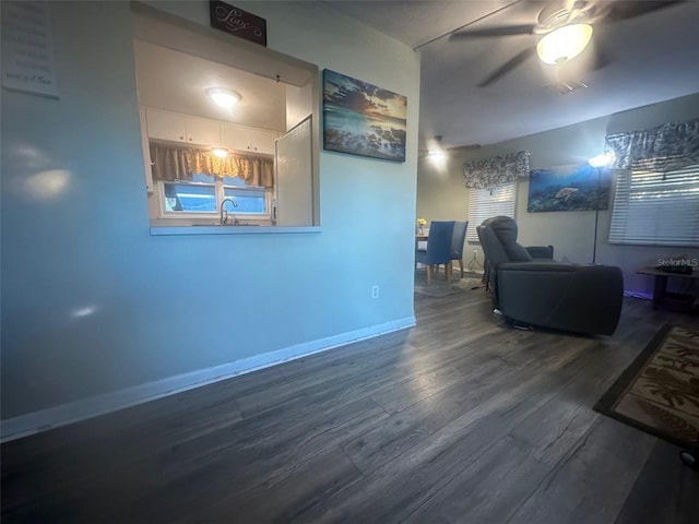 living room with ceiling fan, baseboards, and wood finished floors