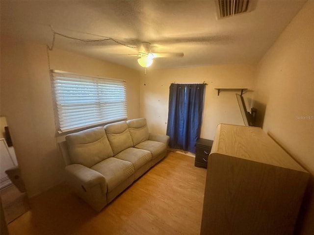 living room with light wood-style floors, visible vents, and a ceiling fan