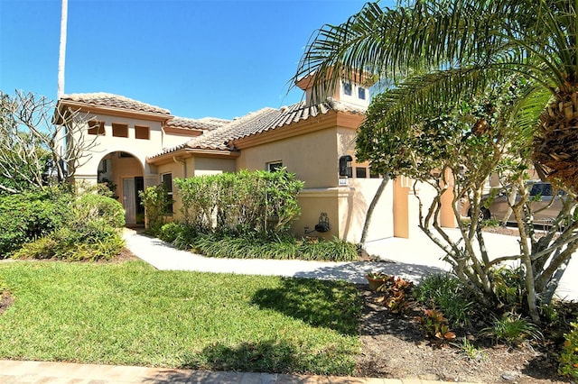 view of front of property featuring a front yard, a tiled roof, fence, and stucco siding