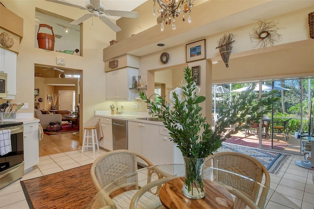 dining area featuring light tile patterned floors, a ceiling fan, and a towering ceiling