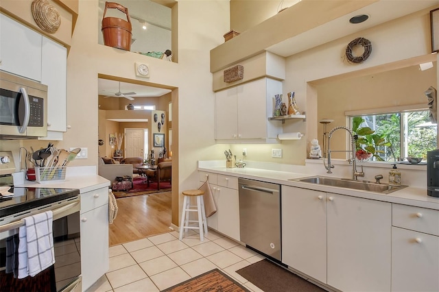 kitchen with a sink, stainless steel appliances, white cabinetry, and light countertops