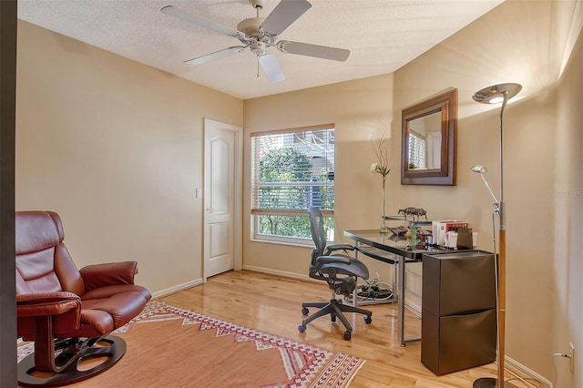 home office with light wood-style flooring, a ceiling fan, baseboards, and a textured ceiling