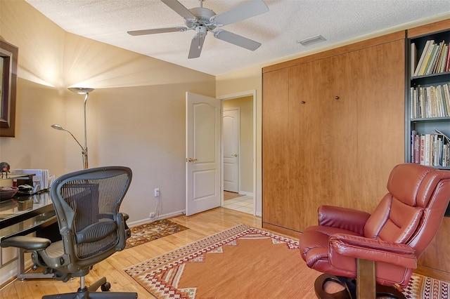 office with visible vents, baseboards, ceiling fan, wood finished floors, and a textured ceiling