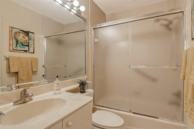 bathroom with combined bath / shower with glass door, toilet, and vanity