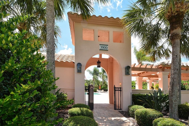 entrance to property featuring a tile roof, a gate, and stucco siding