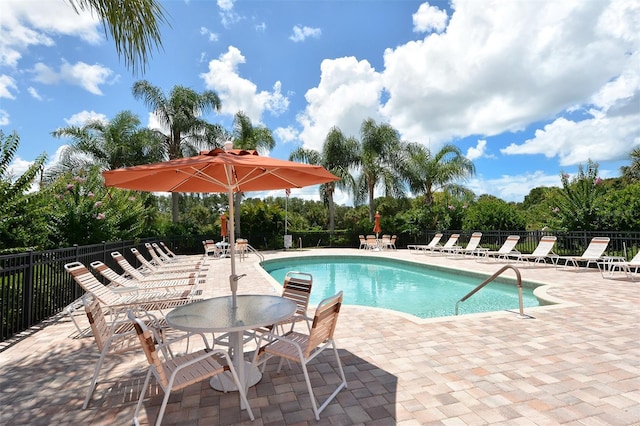 community pool with a patio and fence