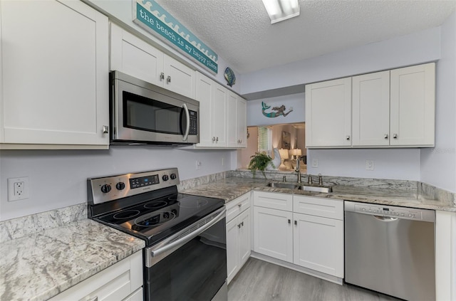 kitchen featuring a textured ceiling, appliances with stainless steel finishes, a sink, and white cabinets