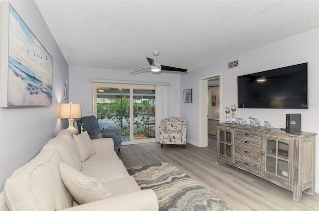 living area featuring visible vents, a ceiling fan, a textured ceiling, wood finished floors, and baseboards