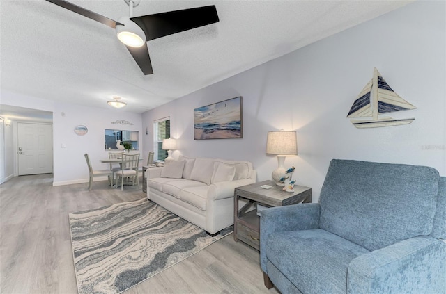 living room featuring light wood-style floors, a textured ceiling, and baseboards