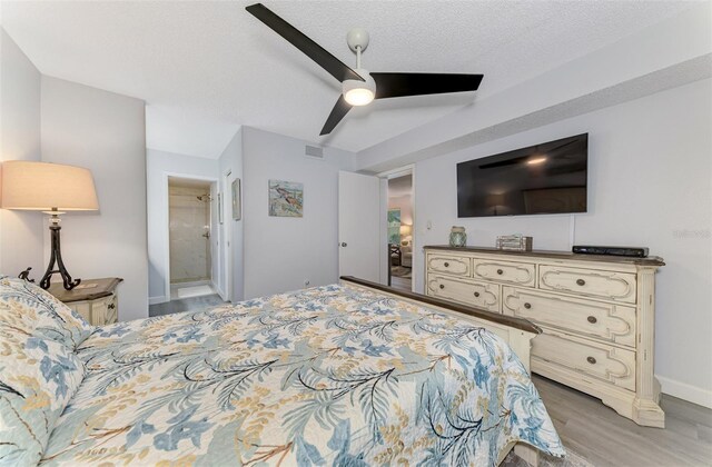 bedroom featuring a textured ceiling, ceiling fan, visible vents, light wood-type flooring, and ensuite bath