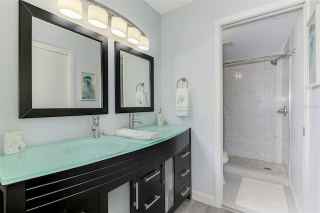 bathroom featuring toilet, baseboards, a tile shower, and vanity