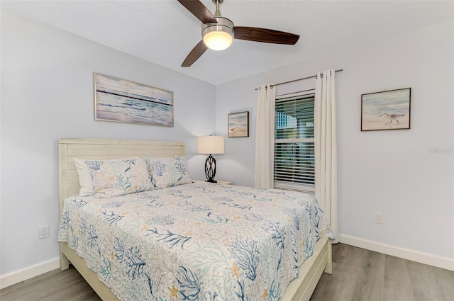 bedroom with a ceiling fan, baseboards, and wood finished floors