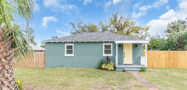 bungalow-style house featuring roof with shingles, a front yard, fence, and stucco siding