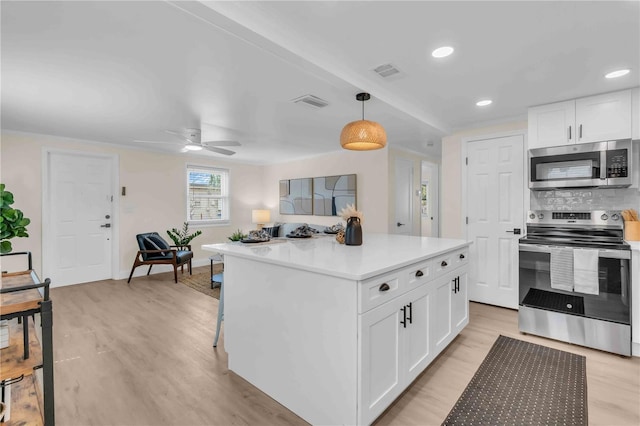 kitchen with light wood finished floors, visible vents, white cabinets, decorative backsplash, and stainless steel appliances