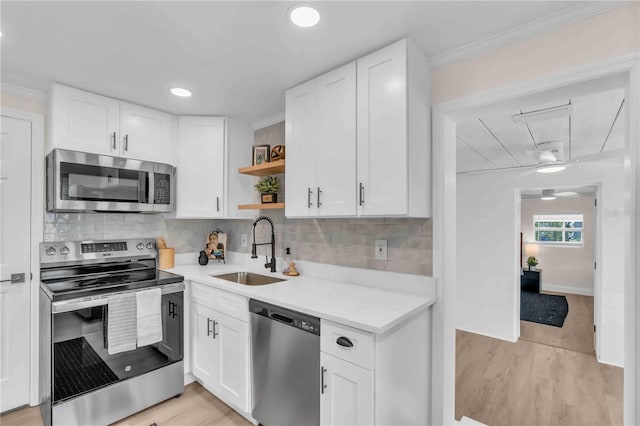 kitchen featuring white cabinets, appliances with stainless steel finishes, light countertops, open shelves, and a sink