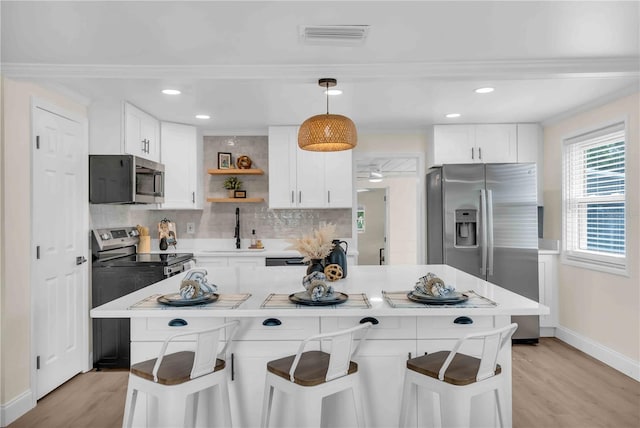 kitchen with white cabinets, visible vents, stainless steel appliances, and decorative backsplash