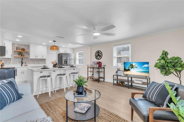 living room with recessed lighting, visible vents, light wood-style flooring, ornamental molding, and ceiling fan