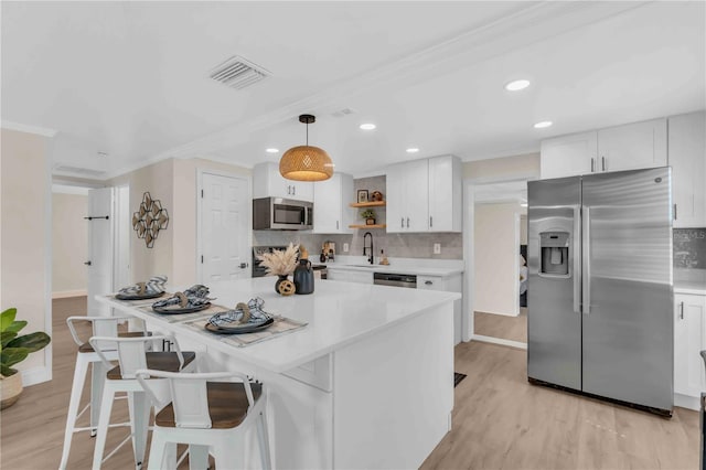 kitchen with light wood finished floors, appliances with stainless steel finishes, white cabinetry, open shelves, and a sink