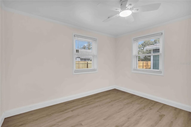 empty room with baseboards, light wood finished floors, a wealth of natural light, and crown molding