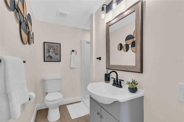 bathroom featuring baseboards, visible vents, toilet, wood finished floors, and vanity