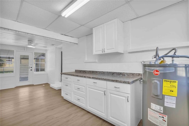 kitchen featuring a paneled ceiling, light wood finished floors, water heater, and white cabinets