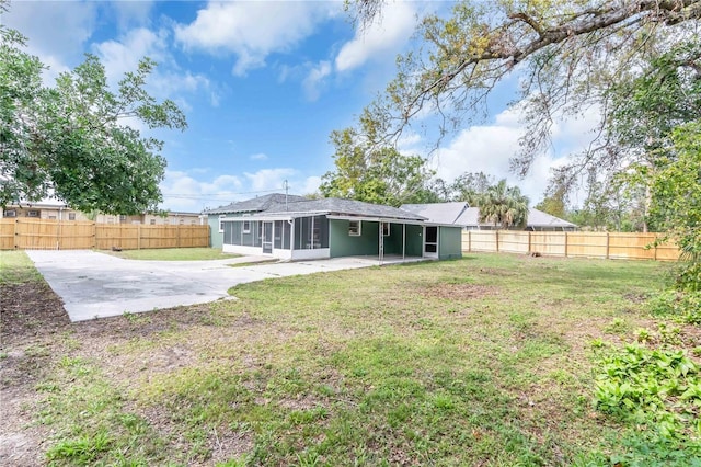 rear view of property featuring a sunroom, a fenced backyard, a lawn, and a patio