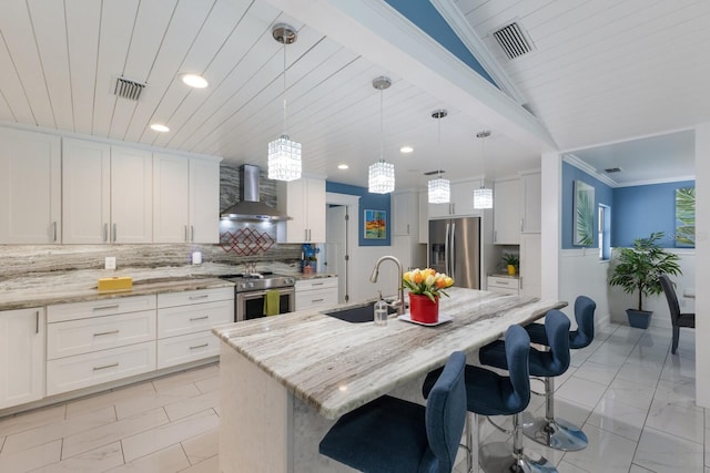 kitchen featuring stainless steel appliances, a sink, visible vents, wall chimney range hood, and backsplash