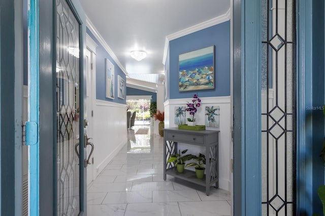 foyer entrance featuring ornamental molding, marble finish floor, and a wainscoted wall