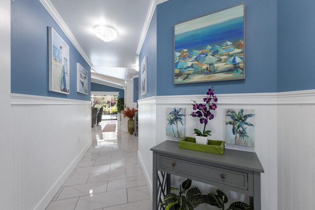 corridor featuring marble finish floor, ornamental molding, and wainscoting