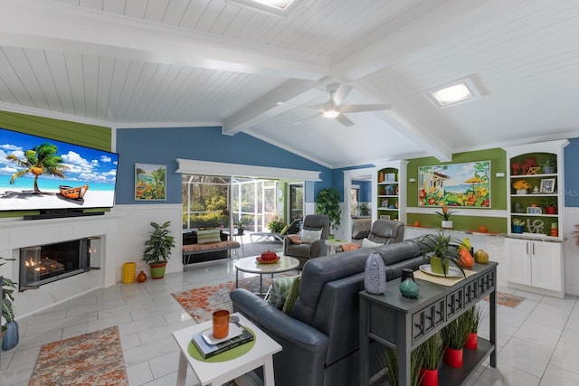 living room featuring a glass covered fireplace, a wainscoted wall, lofted ceiling with beams, and light tile patterned floors