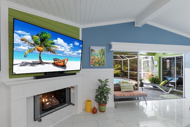 living room with a wainscoted wall, vaulted ceiling with beams, ornamental molding, a sunroom, and a lit fireplace