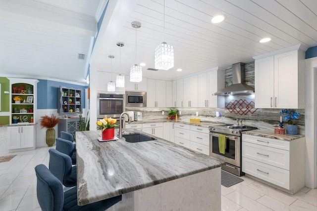 kitchen with wall chimney range hood, white cabinetry, appliances with stainless steel finishes, and a sink