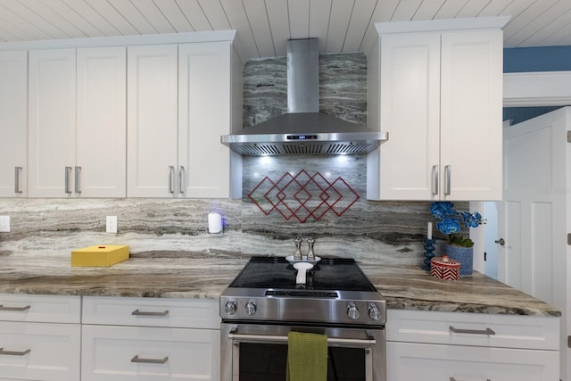 kitchen featuring white cabinetry, stainless steel electric range oven, wall chimney range hood, and decorative backsplash