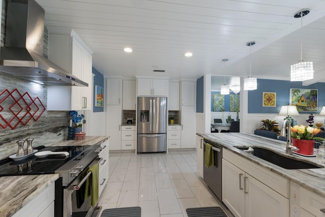 kitchen with tasteful backsplash, white cabinets, stainless steel appliances, wall chimney range hood, and a sink