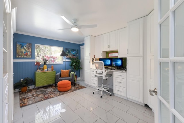 office space with wainscoting, built in study area, ceiling fan, marble finish floor, and crown molding