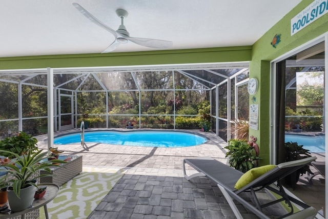 outdoor pool featuring a patio, glass enclosure, and a ceiling fan