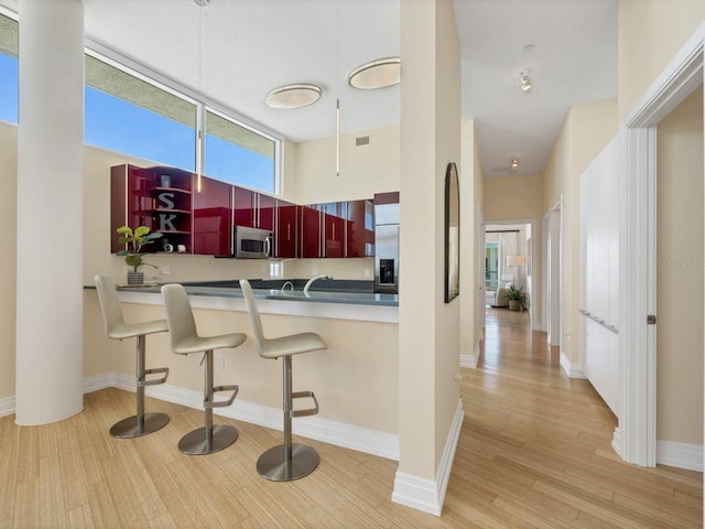 6512 Midnight Pass Rd Unit 504, Sarasota, FL 34242 - kitchen with appliances with stainless steel finishes, light wood finished floors, reddish brown cabinets, and a breakfast bar area