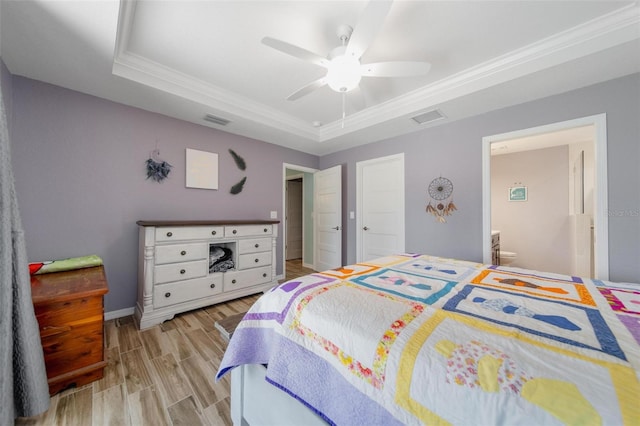 bedroom featuring visible vents, a raised ceiling, ornamental molding, and light wood finished floors