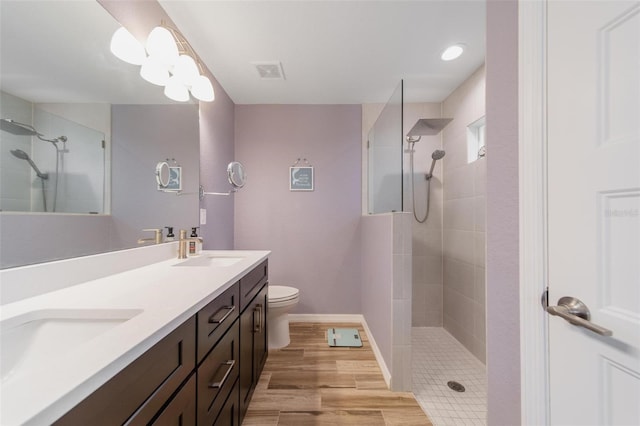 bathroom with double vanity, wood finished floors, walk in shower, and a sink