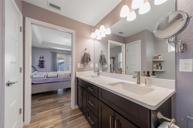 ensuite bathroom with visible vents, connected bathroom, and a sink