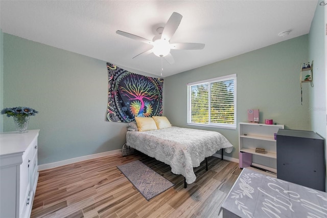 bedroom featuring light wood-style flooring, baseboards, and ceiling fan