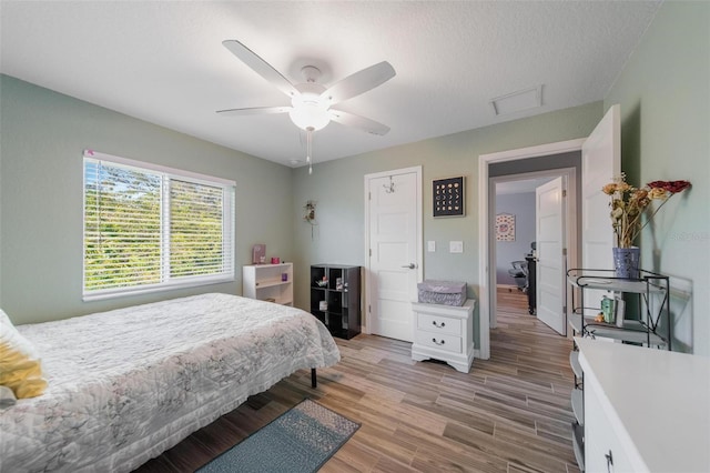 bedroom featuring a textured ceiling, a ceiling fan, and light wood-style floors