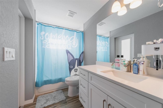 full bath featuring vanity, toilet, wood finished floors, and visible vents