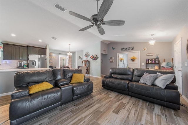 living area featuring visible vents, lofted ceiling, baseboards, and light wood finished floors