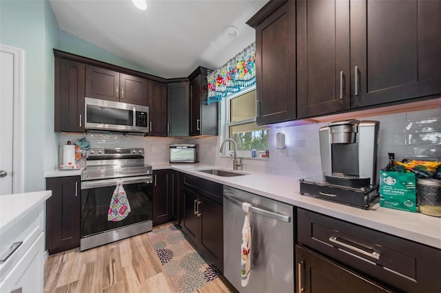 kitchen with light wood-style flooring, a sink, stainless steel appliances, light countertops, and dark brown cabinetry