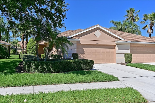 view of front of home featuring a garage, driveway, a tiled roof, stucco siding, and a front yard