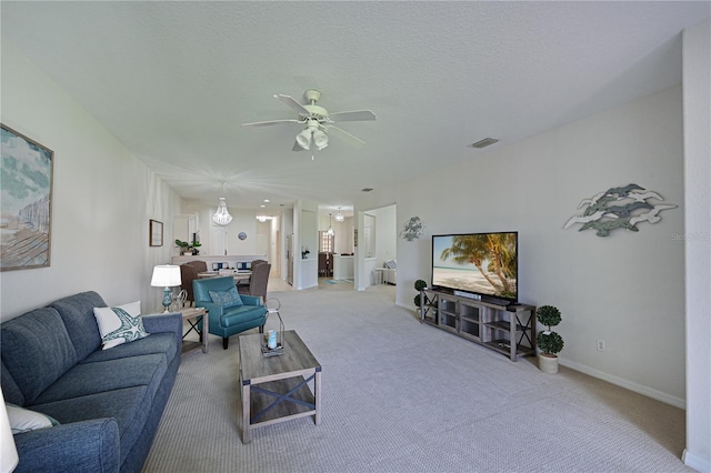 carpeted living area with ceiling fan, a textured ceiling, visible vents, and baseboards