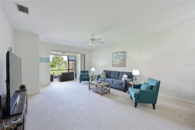 carpeted living room with a ceiling fan, visible vents, a textured ceiling, and baseboards