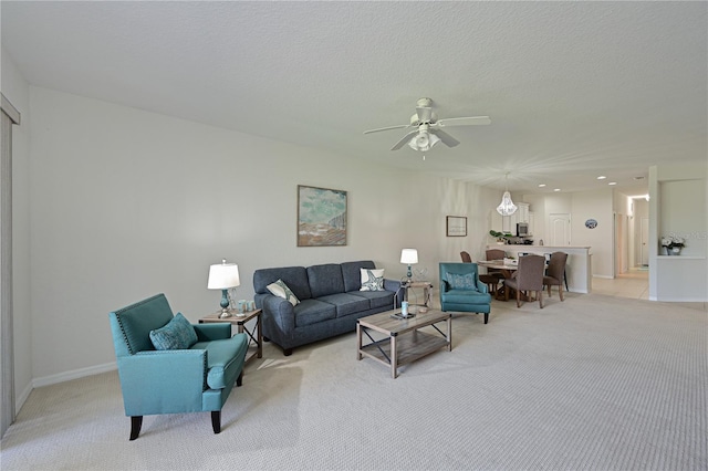 living room with light carpet, ceiling fan, and a textured ceiling