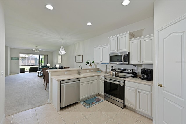 kitchen with light colored carpet, appliances with stainless steel finishes, open floor plan, a peninsula, and a sink